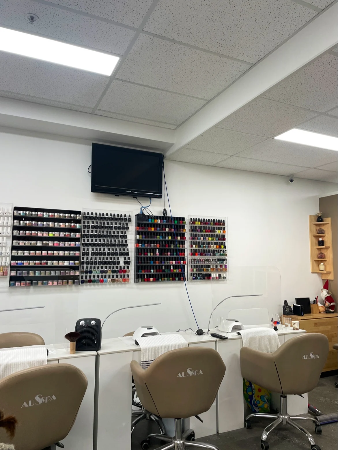 Noble Nails and Beauty interior — manicure stations with AUSSPA chairs beneath four racks of hundreds of polish bottles, Brunswick VIC