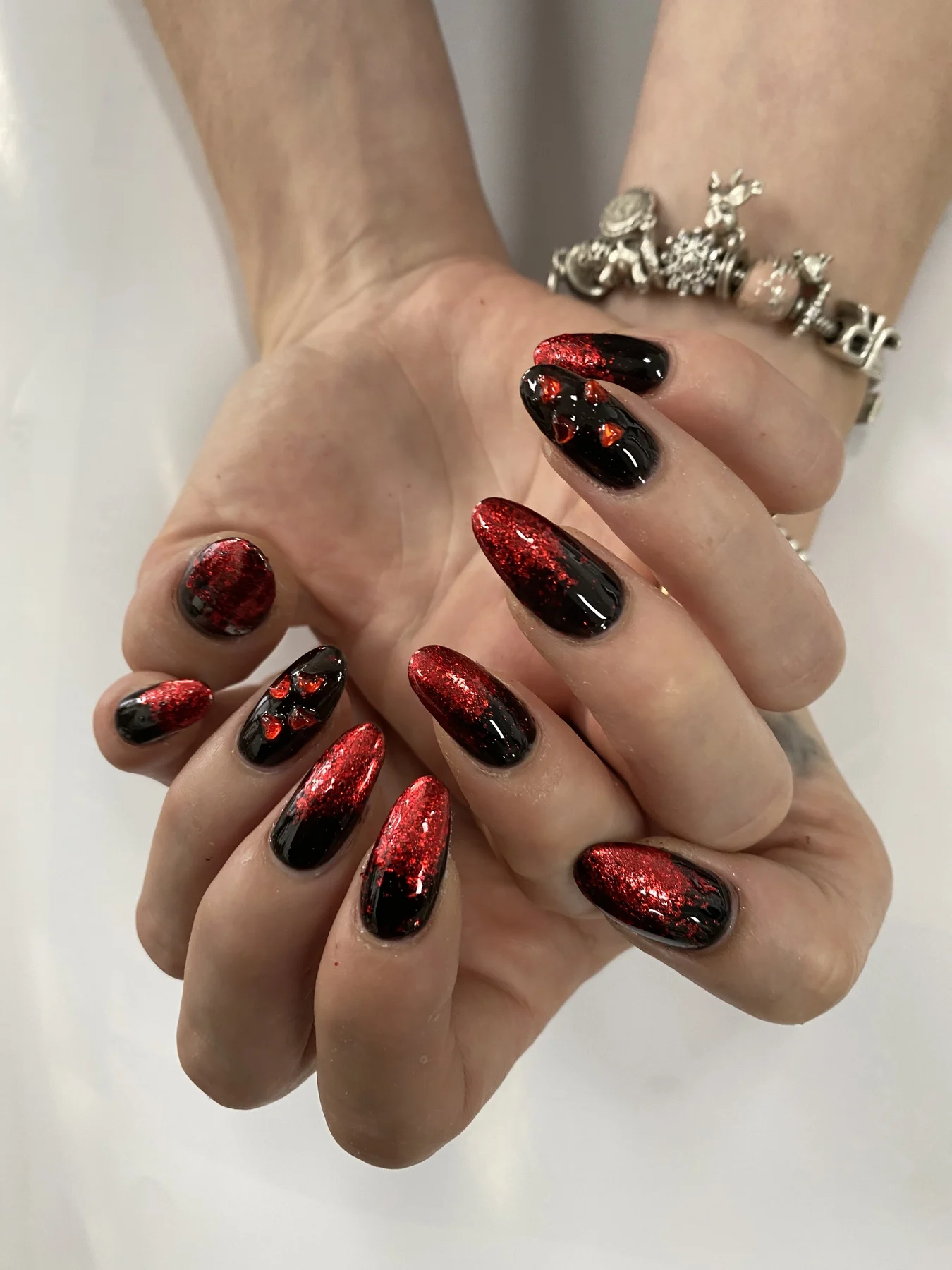 Red-glitter and black ombre nails with charm bracelet