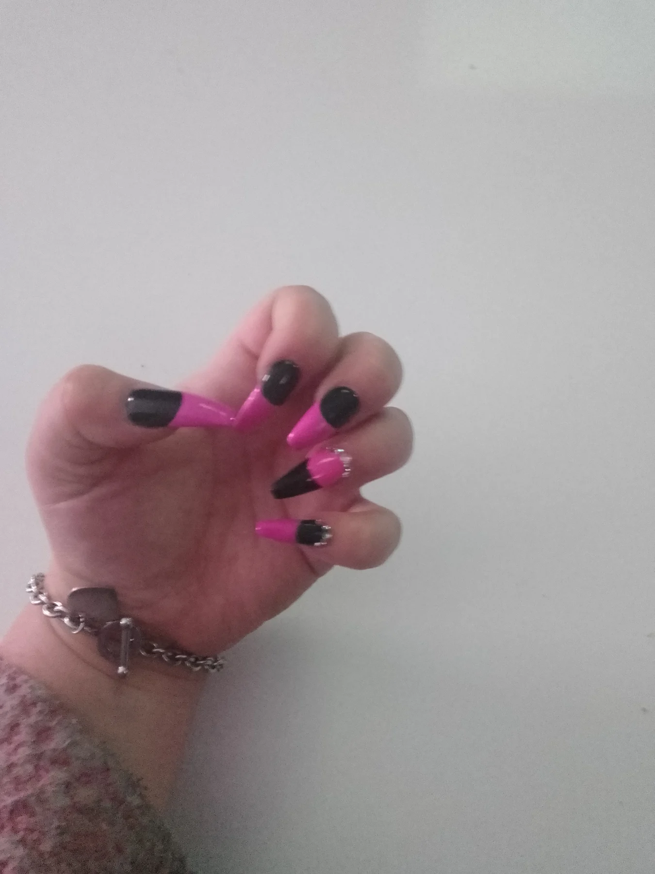 Hot-pink and black long nails with silver chain bracelet