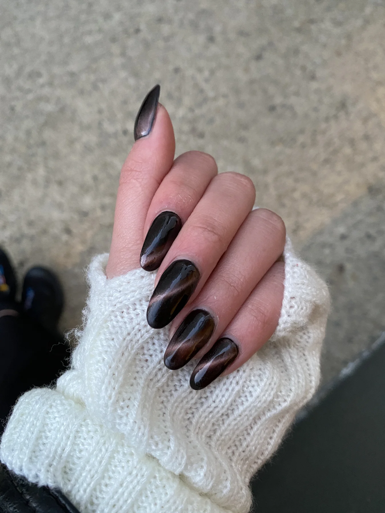 Dark-brown cat-eye stiletto nails from white knit sleeve