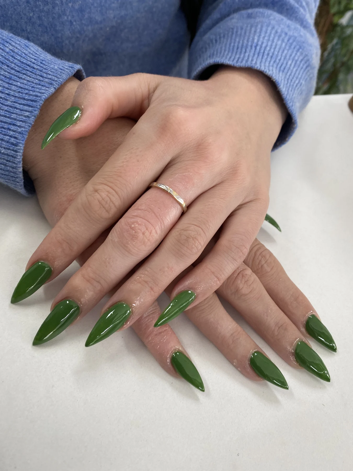 Long olive-green stiletto nails with gold ring