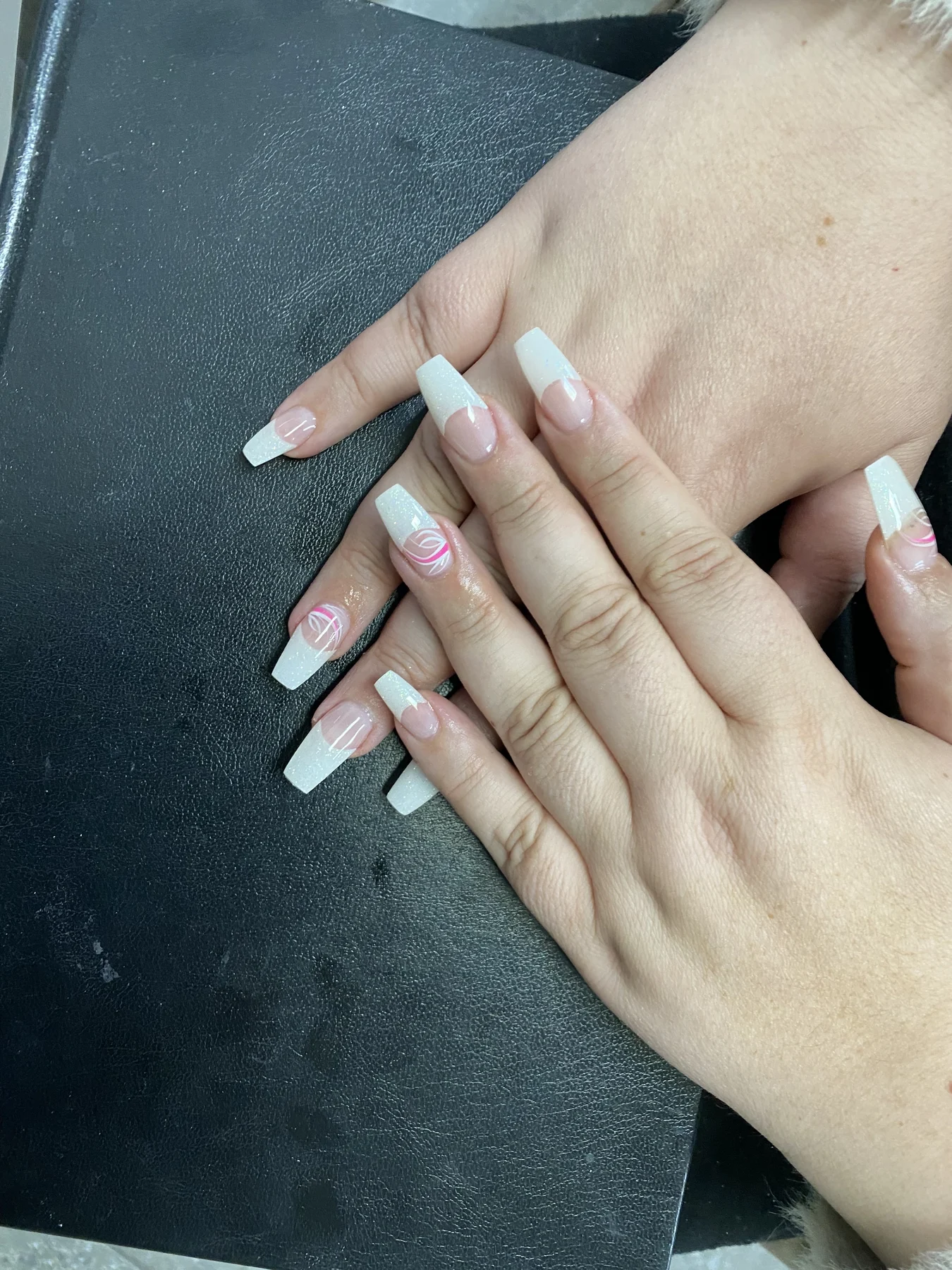 White-and-pink swirl french nails on black leather