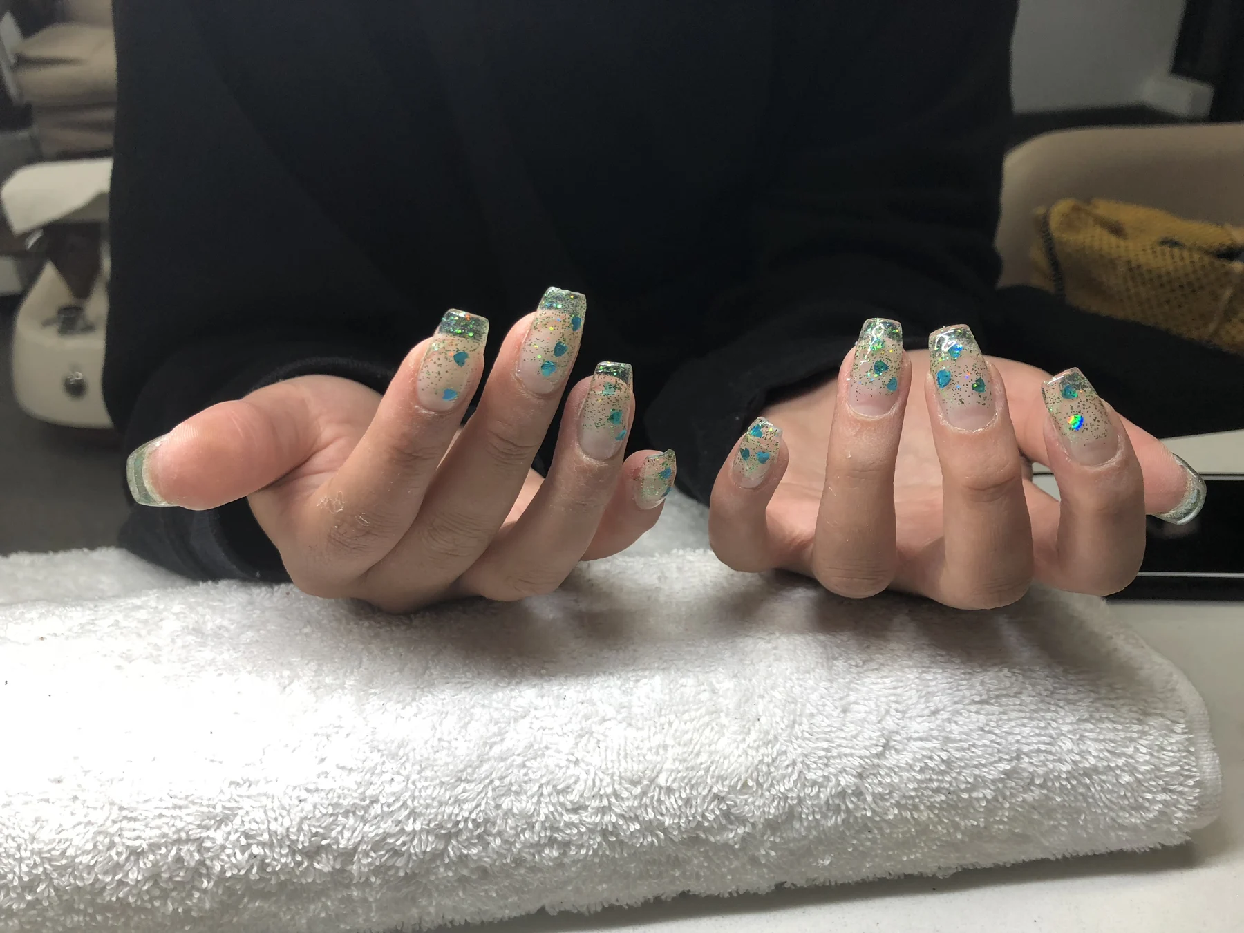 Teal patterned nails at manicure station on white towel