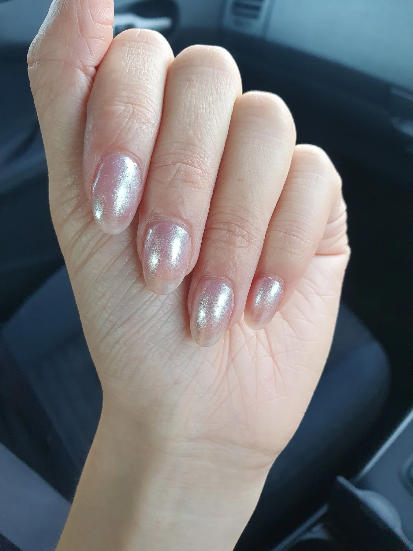 Pearl-white nails photographed in a car