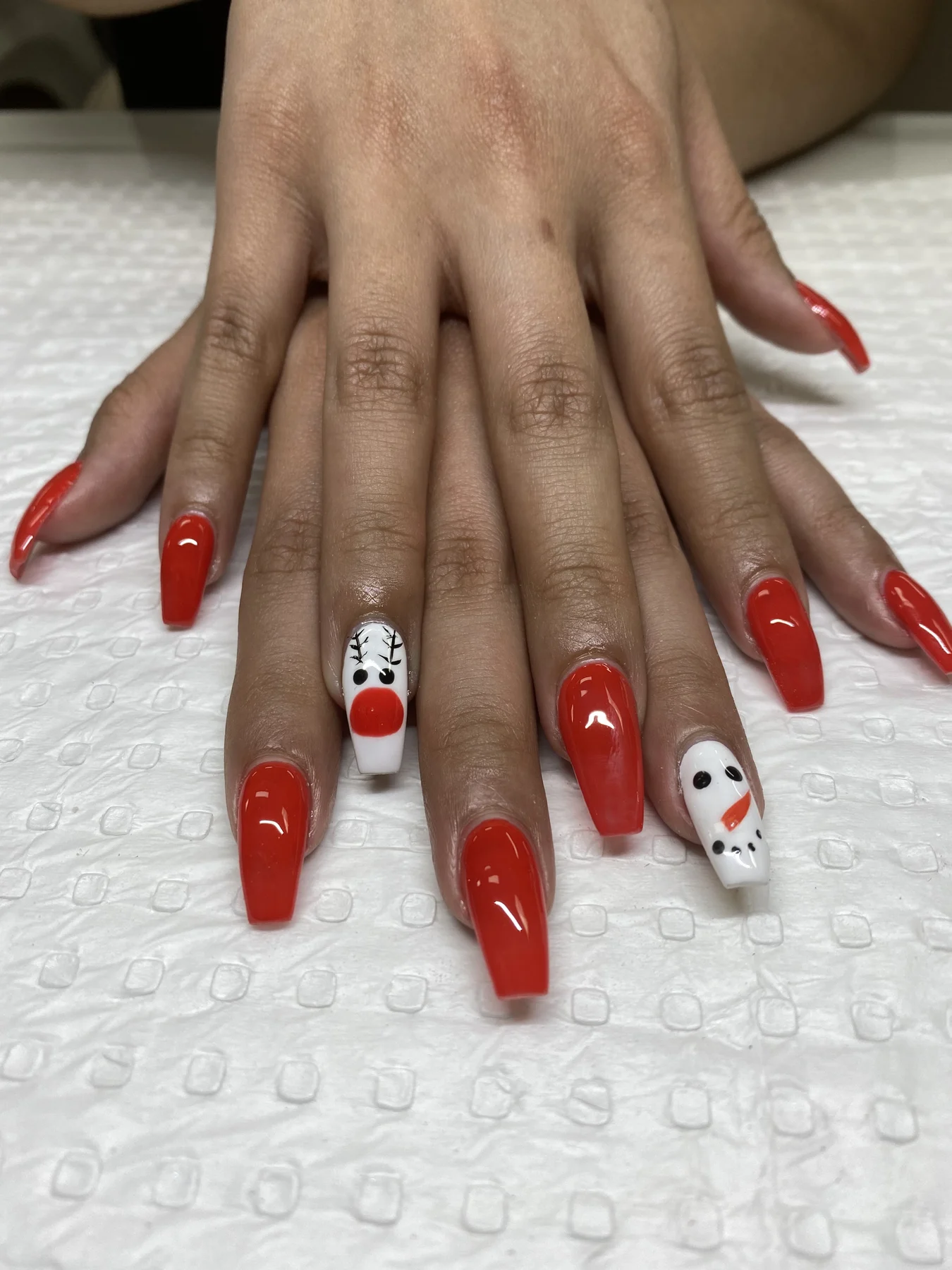 Long scarlet nails with reindeer and snowman accent art on towel
